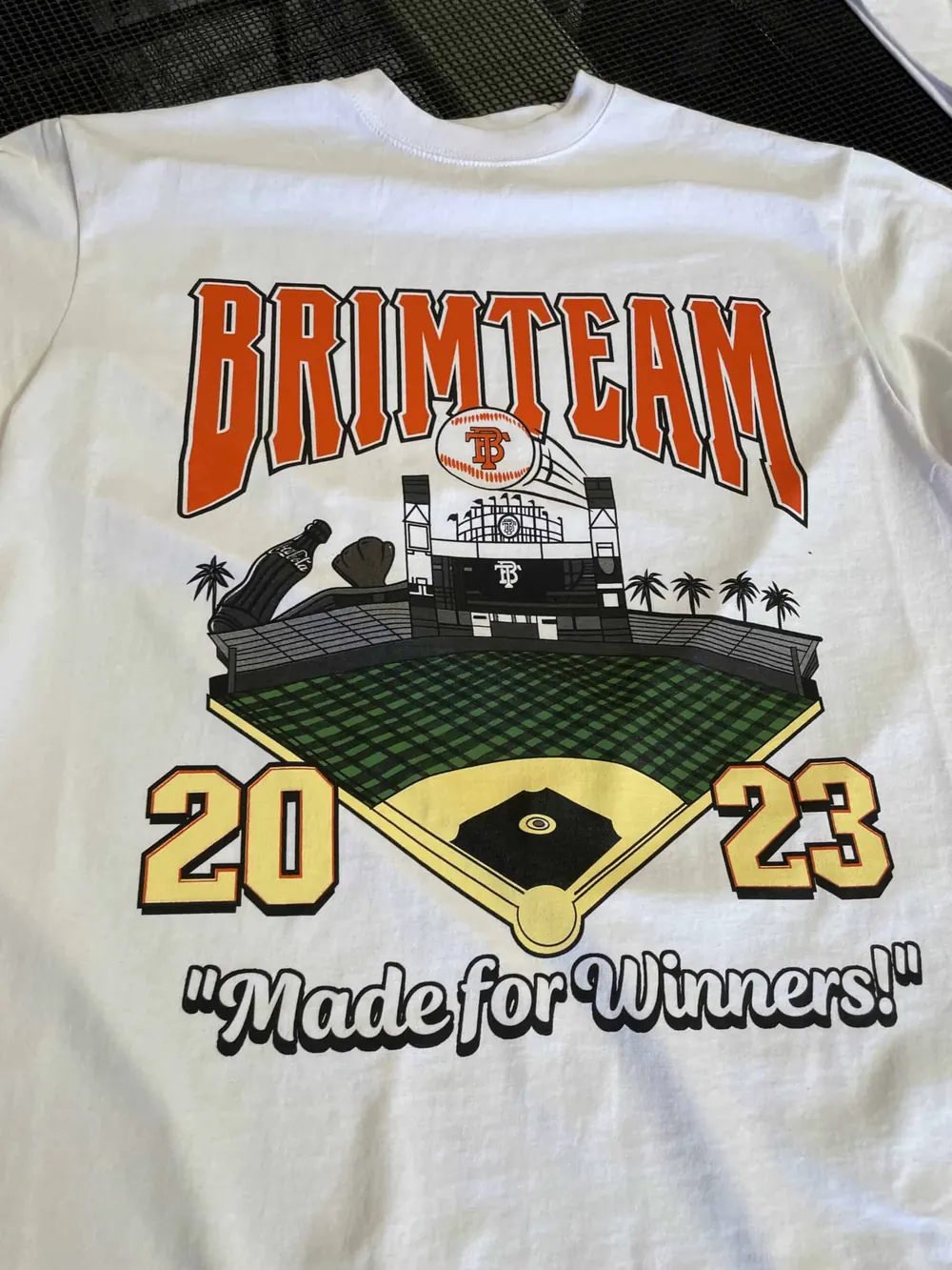 White tee printed for Brim Team with a 2023 ballpark design