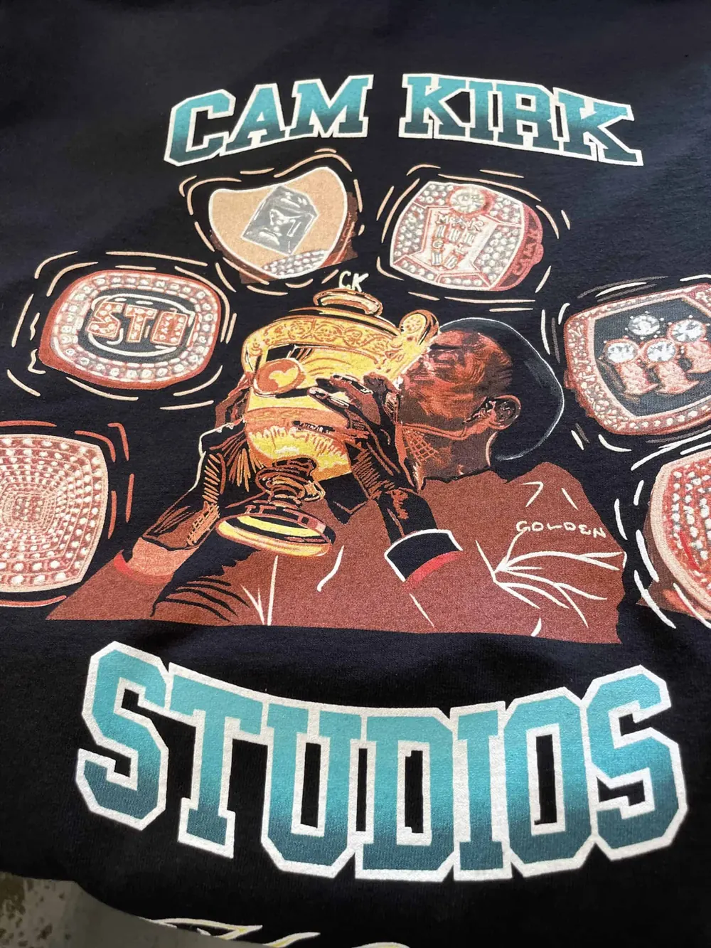 Black tee printed for Cam Kirk Studios with a full-color illustration