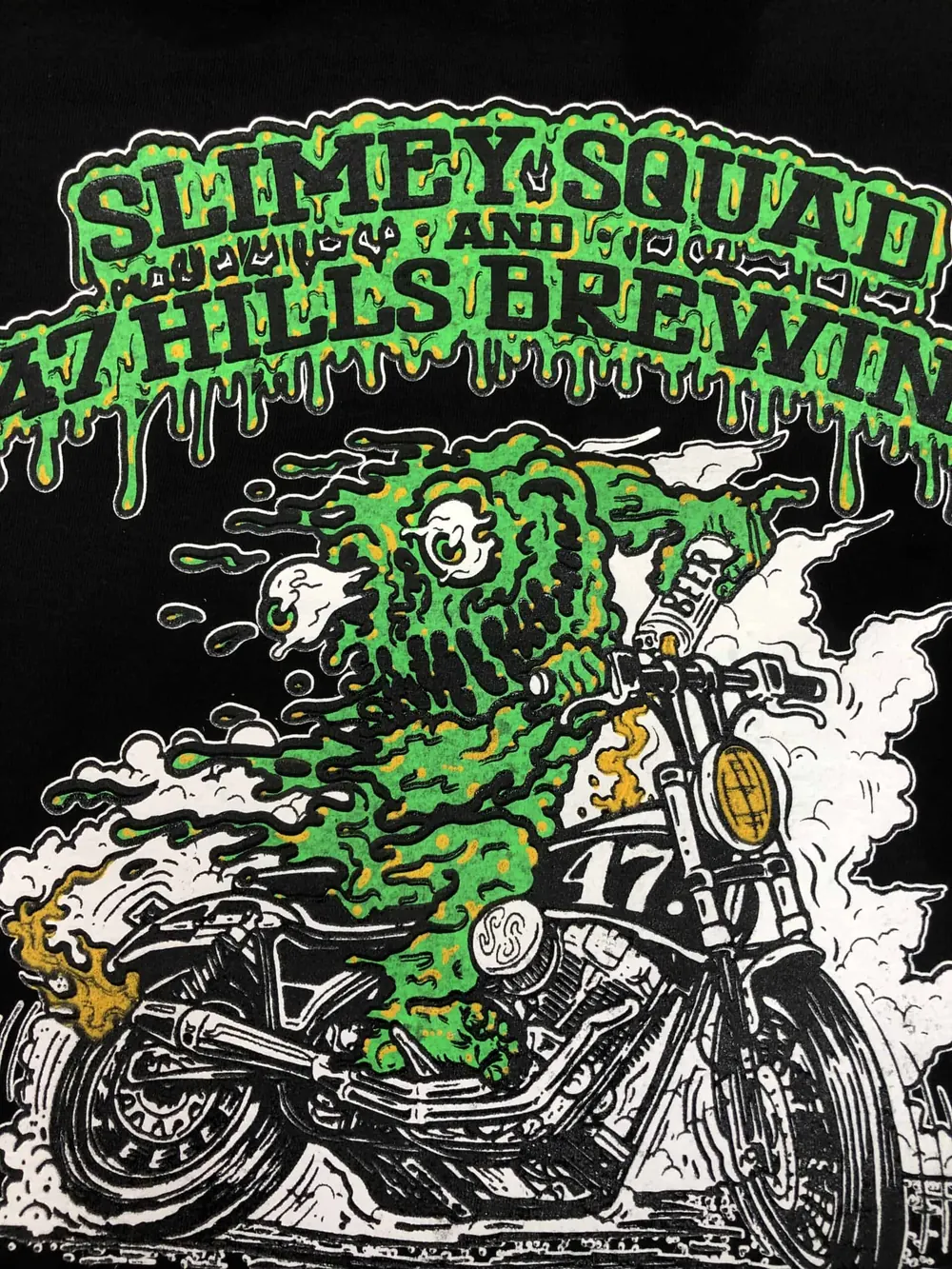Black tee printed for Seven Hills Brewing with a green slime rider on a motorcycle